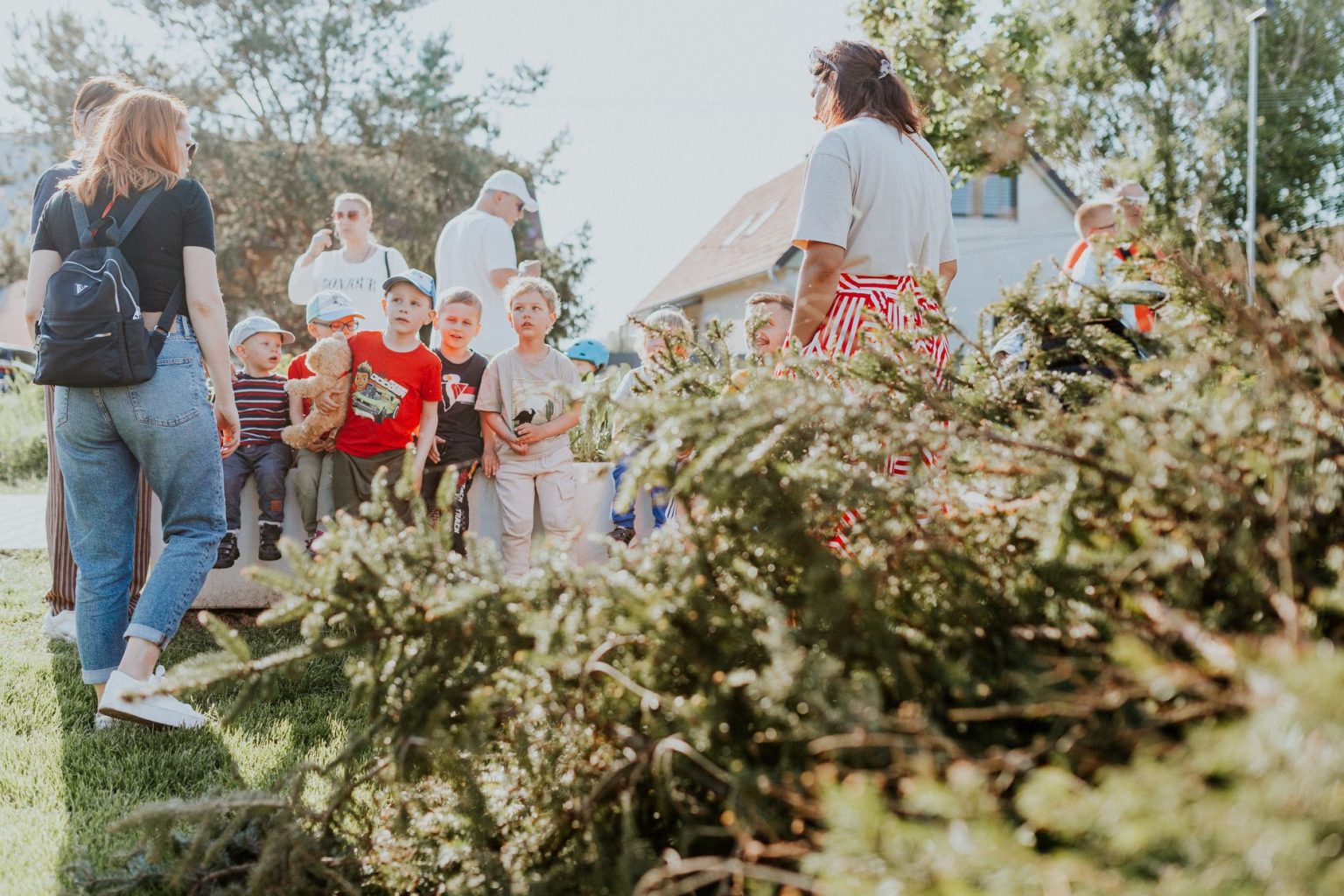 Crianças e adultos participam de uma atividade educativa ao ar livre, cercados por vegetação.