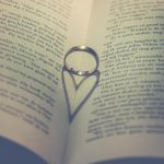 Anéis sobre as páginas de um livro, em uma composição associada a amor, pedido de casamento e união.