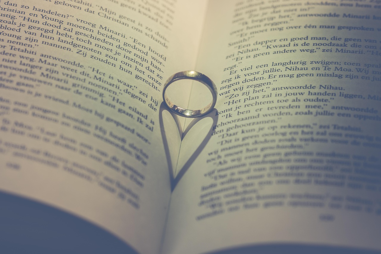 Anéis sobre as páginas de um livro, em uma composição associada a amor, pedido de casamento e união.